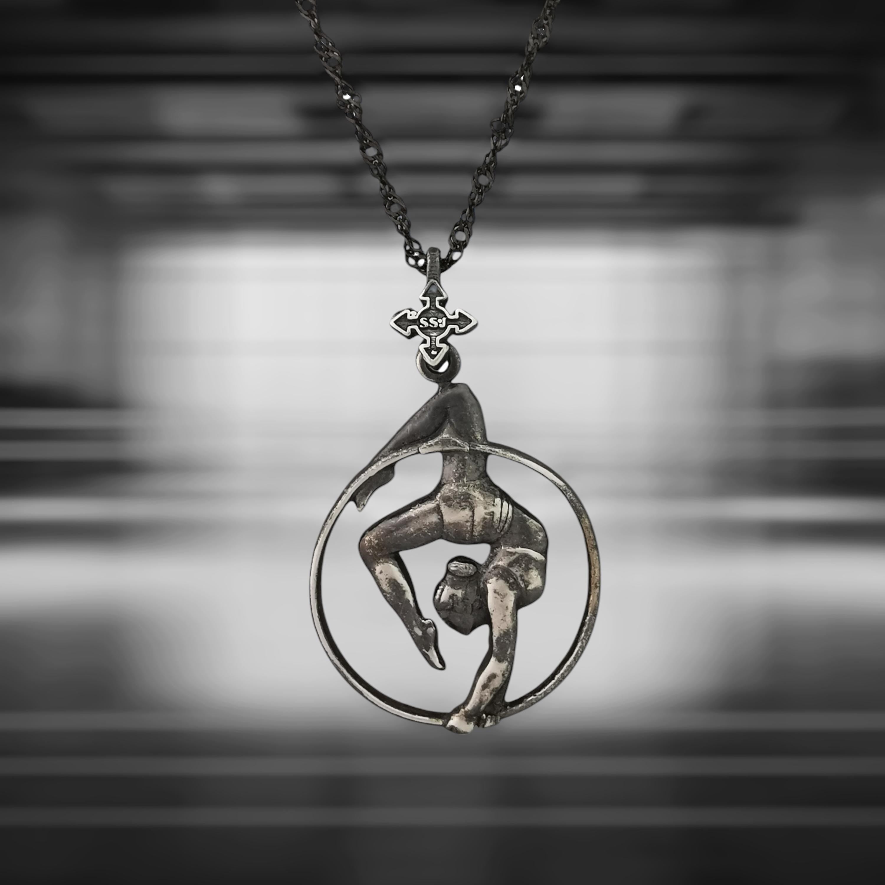 Vintage-style aerial hoop necklace in patinated 925 sterling silver — a bold and soulful pendant capturing the expressive grace of aerial performance. Designed for women who blend movement with meaning, elegance with strength.

This handcrafted piece features a female aerialist mid-performance in an upside-down pose, radiating poise, power, and emotional depth. The aged silver finish adds timeless charm and artistic character — perfect for free spirits and lovers of vintage aesthetics.
