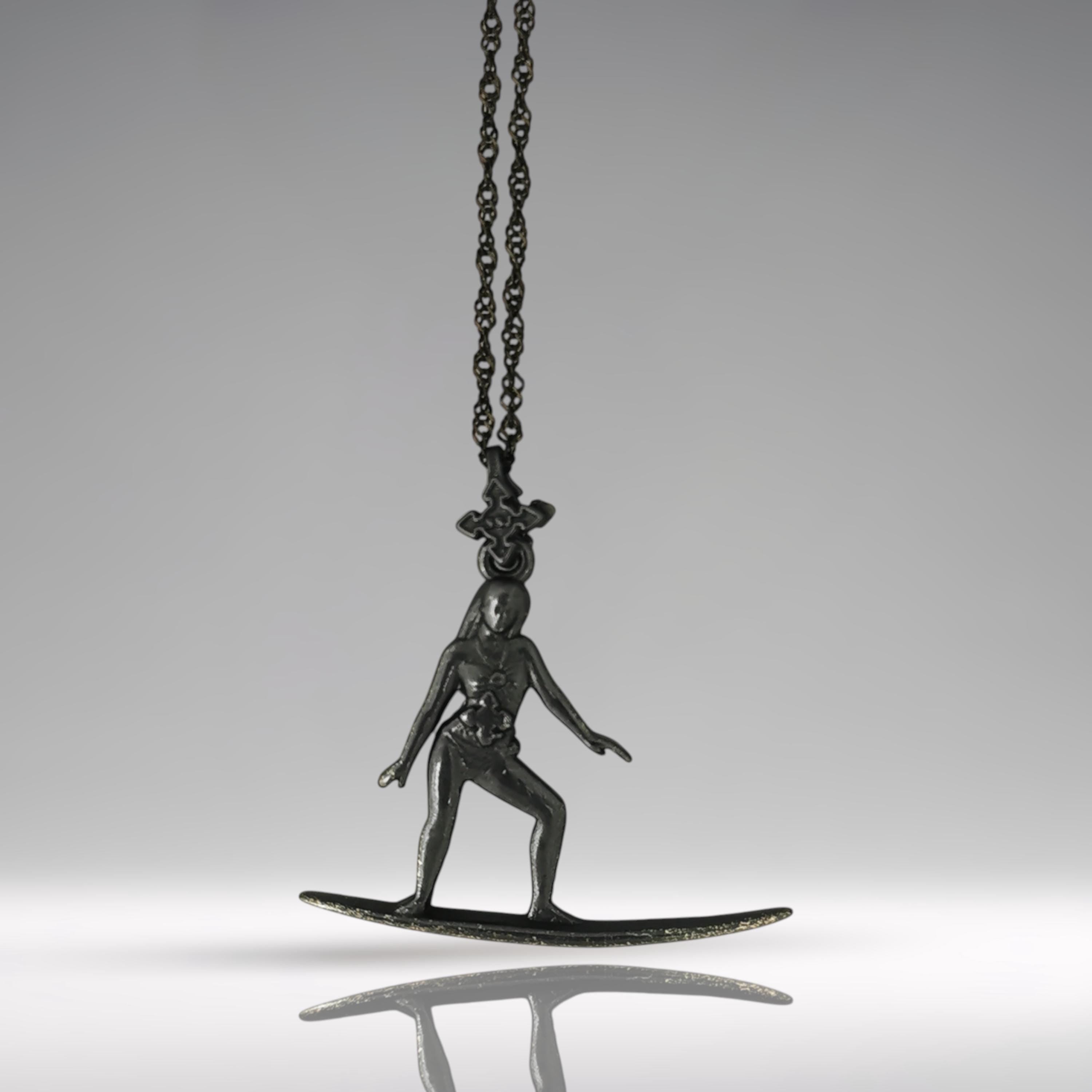 Black oxidized surf necklace handcrafted in solid 925 sterling silver — a sleek and soulful pendant celebrating the thrill of wave riding and the freedom of the open sea.

This expressive design captures a poised female surfer mid-ride, her body aligned with the board in perfect harmony. The dark matte finish adds mystery and edge, turning the piece into a powerful symbol of flow, balance, and untamed spirit. A tribute to women who live for the ocean breeze and move with fearless grace.