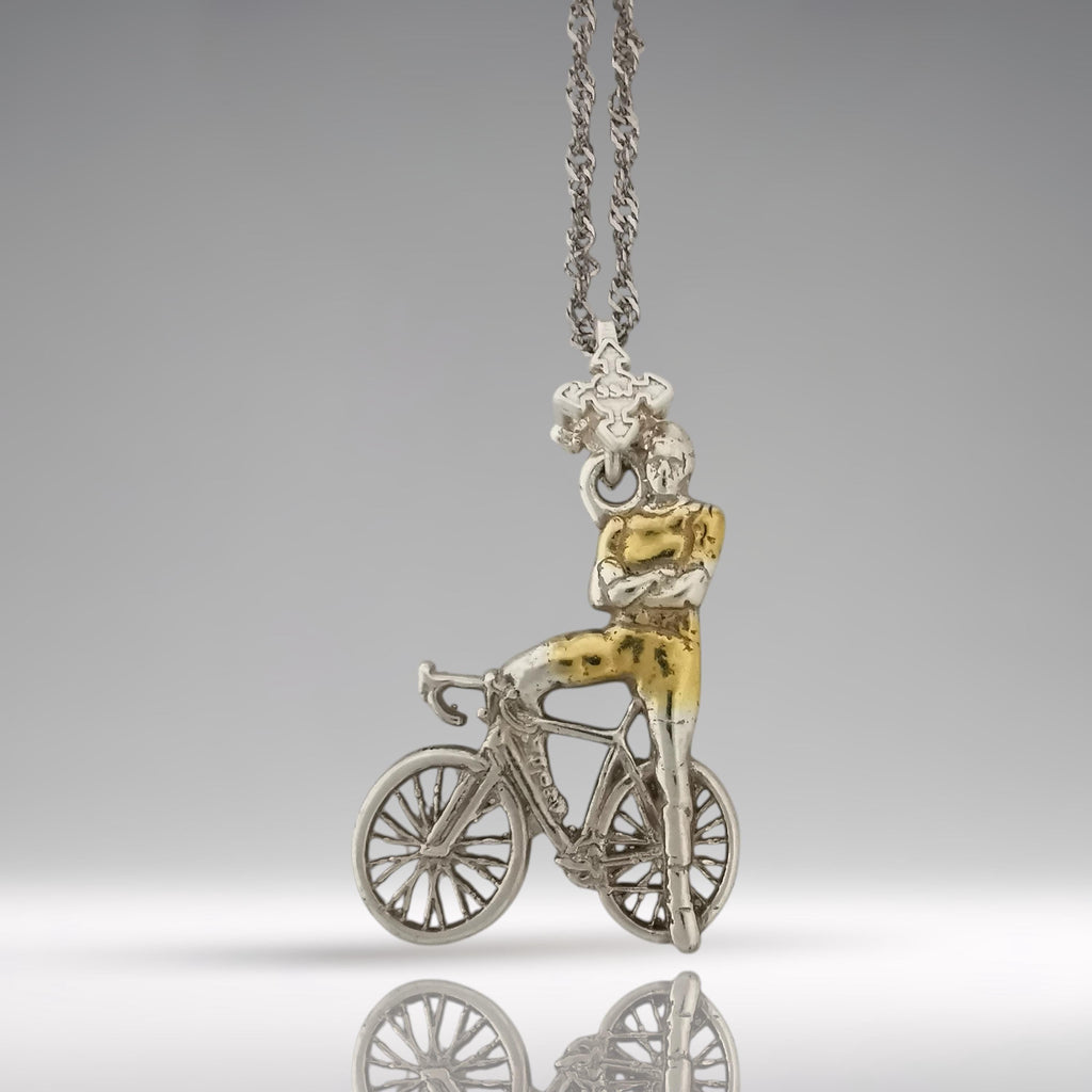Two-tone cyclist necklace handcrafted from solid 925 sterling silver with partial gold plating — a modern and elegant pendant for men who live with energy, intention, and style.

This unique design features a proud rider standing beside his bicycle, arms confidently crossed. The subtle gold accents highlight the rider’s form and bike details, creating a bold contrast with the polished silver. It’s a wearable tribute to strength, focus, and personal discipline
